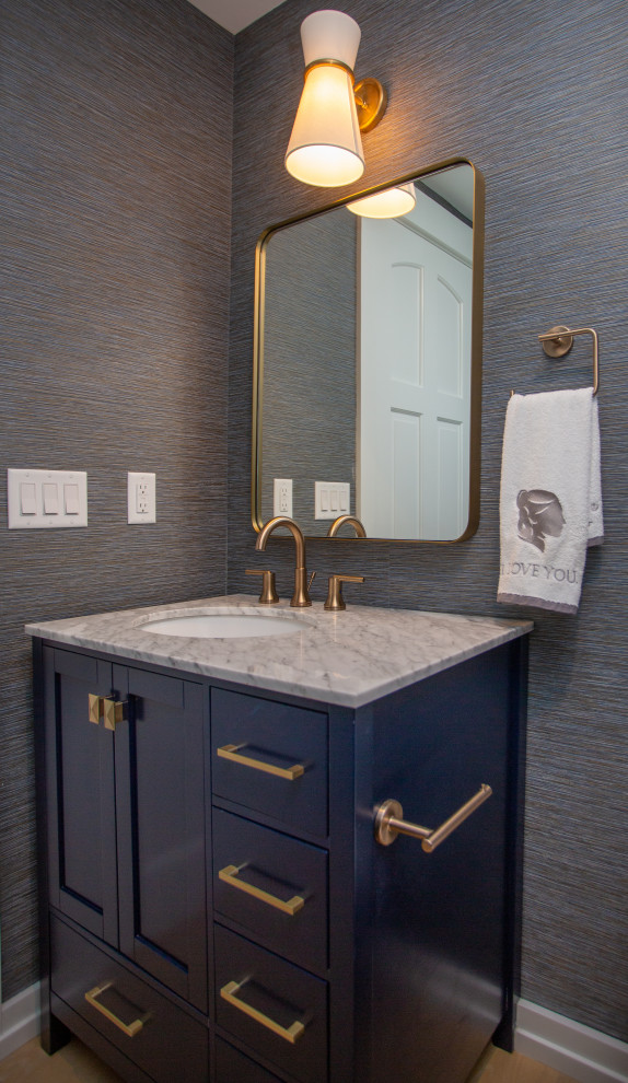 Imagen de aseo de pie contemporáneo pequeño con armarios con paneles empotrados, puertas de armario azules, paredes azules, lavabo bajoencimera, encimera de mármol y papel pintado