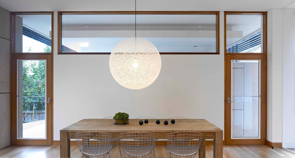 This is an example of a contemporary dining room in Melbourne with white walls and light hardwood floors.