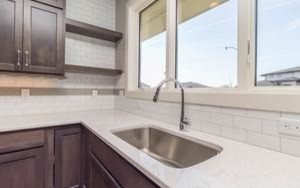 Example of a mid-sized transitional l-shaped medium tone wood floor open concept kitchen design with an undermount sink, shaker cabinets, dark wood cabinets, marble countertops, white backsplash, subway tile backsplash, stainless steel appliances and an island