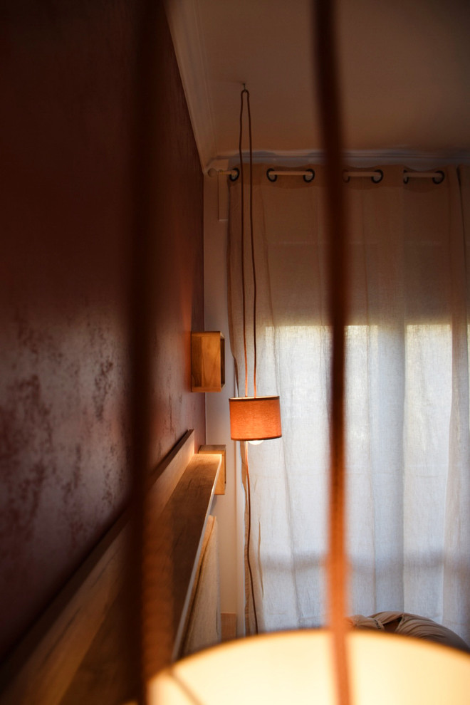 Cette photo montre une chambre parentale tendance de taille moyenne avec un mur rouge, parquet clair et un sol marron.