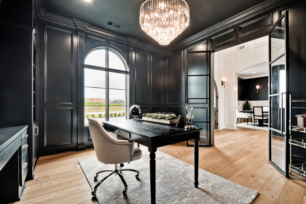 This is an example of a large transitional study room in Other with black walls, light hardwood floors, a built-in desk and panelled walls.