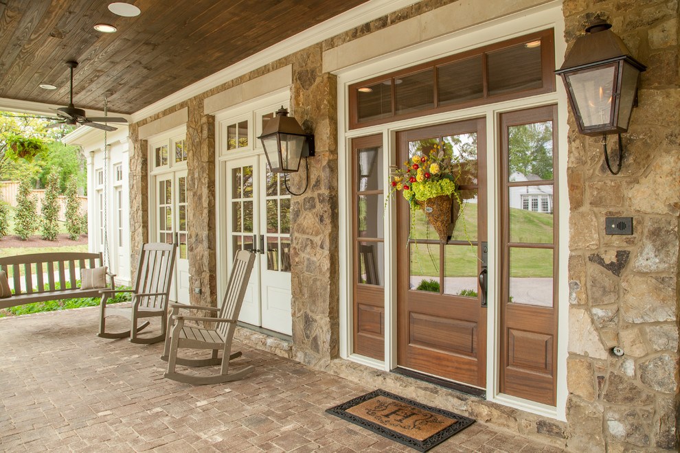 This is an example of a mid-sized traditional front yard verandah in Nashville with brick pavers and a roof extension.