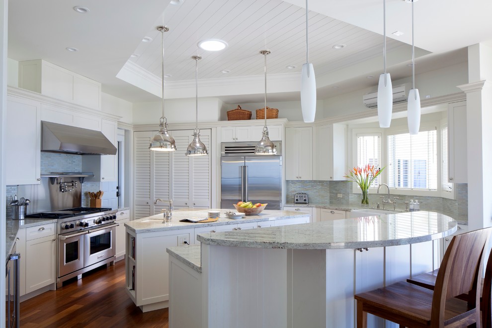 This is an example of a tropical kitchen in Hawaii with a farmhouse sink, shaker cabinets, white cabinets, multi-coloured splashback, stainless steel appliances and matchstick tile splashback.