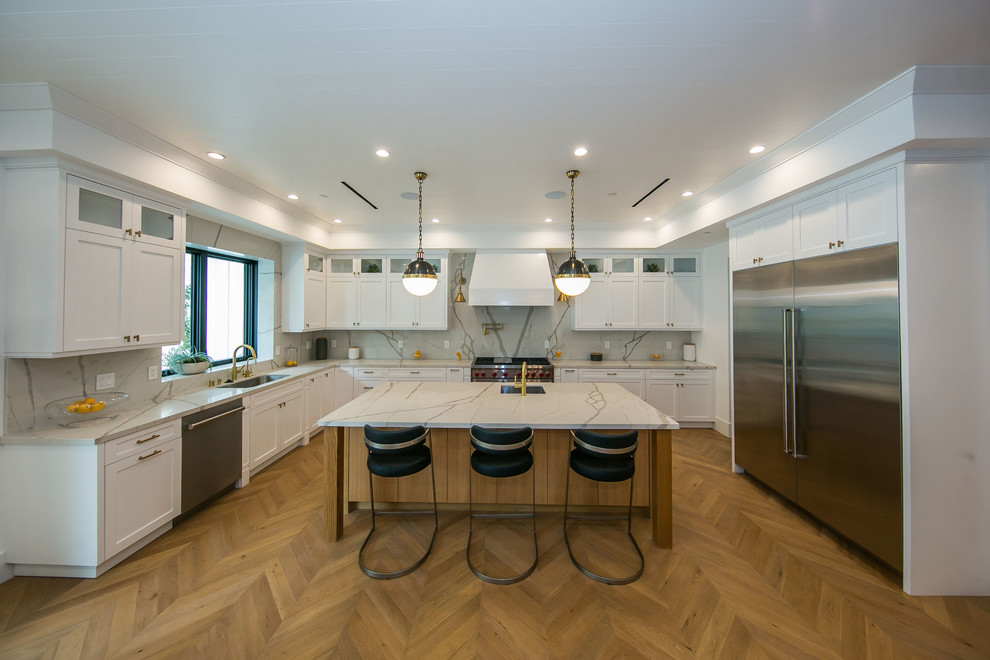 Inspiration for a large modern u-shaped eat-in kitchen in Los Angeles with a drop-in sink, raised-panel cabinets, white cabinets, granite benchtops, white splashback, granite splashback, stainless steel appliances, porcelain floors, with island, beige floor, white benchtop and wood.
