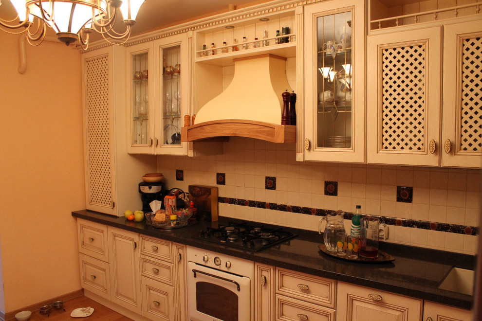 Photo of a large traditional l-shaped enclosed kitchen in Moscow with a submerged sink, glass-front cabinets, beige cabinets, composite countertops, multi-coloured splashback, ceramic splashback, white appliances, medium hardwood flooring, no island, brown floors and multicoloured worktops.