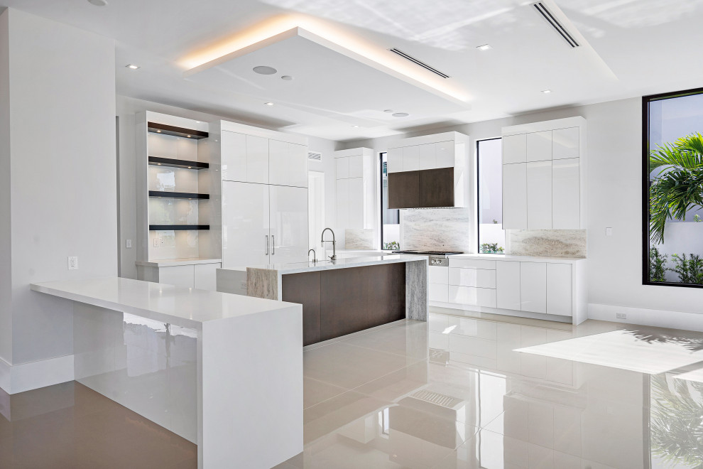 Inspiration for a large modern open plan kitchen in Miami with a farmhouse sink, white cabinets, granite benchtops, multi-coloured splashback, granite splashback, white appliances, marble floors, with island, grey floor, white benchtop and recessed.