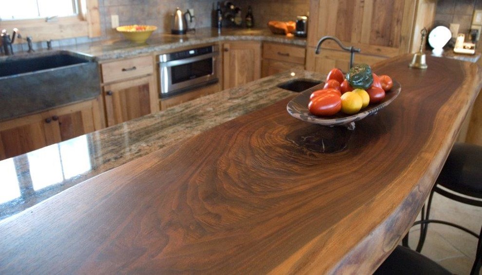 Example of a large mountain style u-shaped eat-in kitchen design in Denver with beige walls, an island, raised-panel cabinets, wood countertops, stainless steel appliances, a drop-in sink, brown cabinets, beige backsplash and ceramic backsplash
