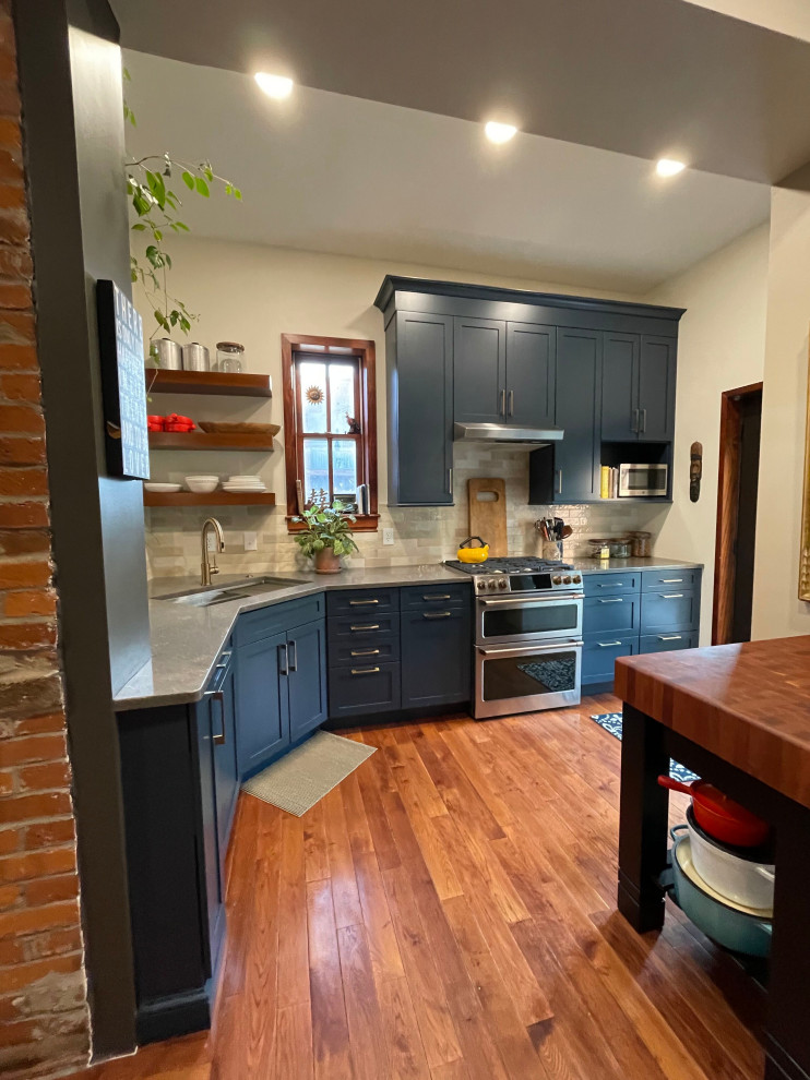 Example of a small minimalist l-shaped medium tone wood floor and brown floor eat-in kitchen design in St Louis with an undermount sink, recessed-panel cabinets, blue cabinets, quartzite countertops, beige backsplash, ceramic backsplash, stainless steel appliances, no island and gray countertops