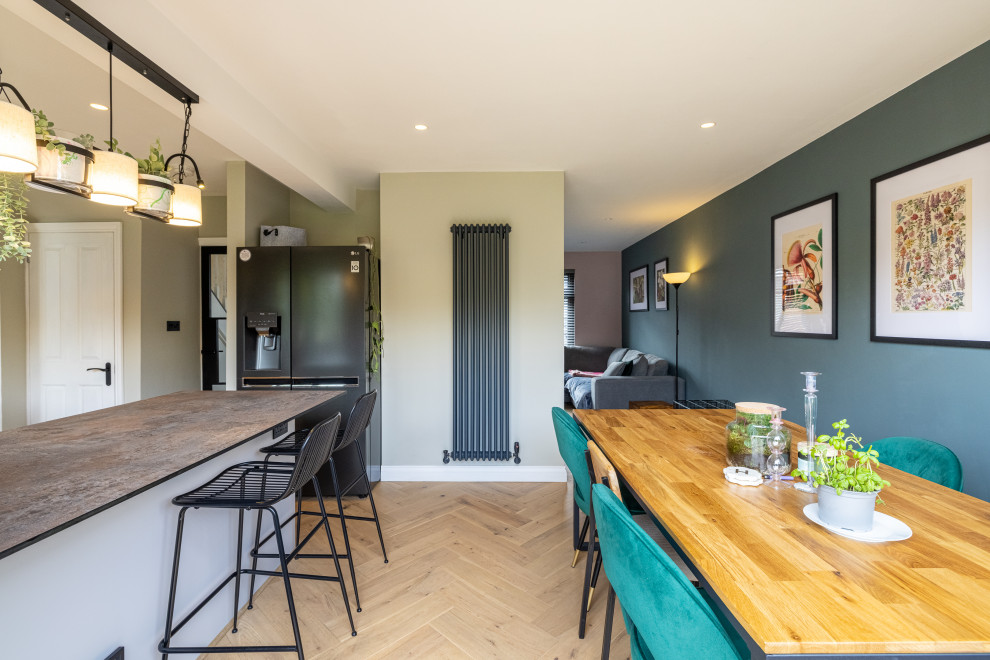Immagine di una cucina abitabile design di medie dimensioni con lavello da incasso, elettrodomestici neri, parquet chiaro, penisola e pavimento beige