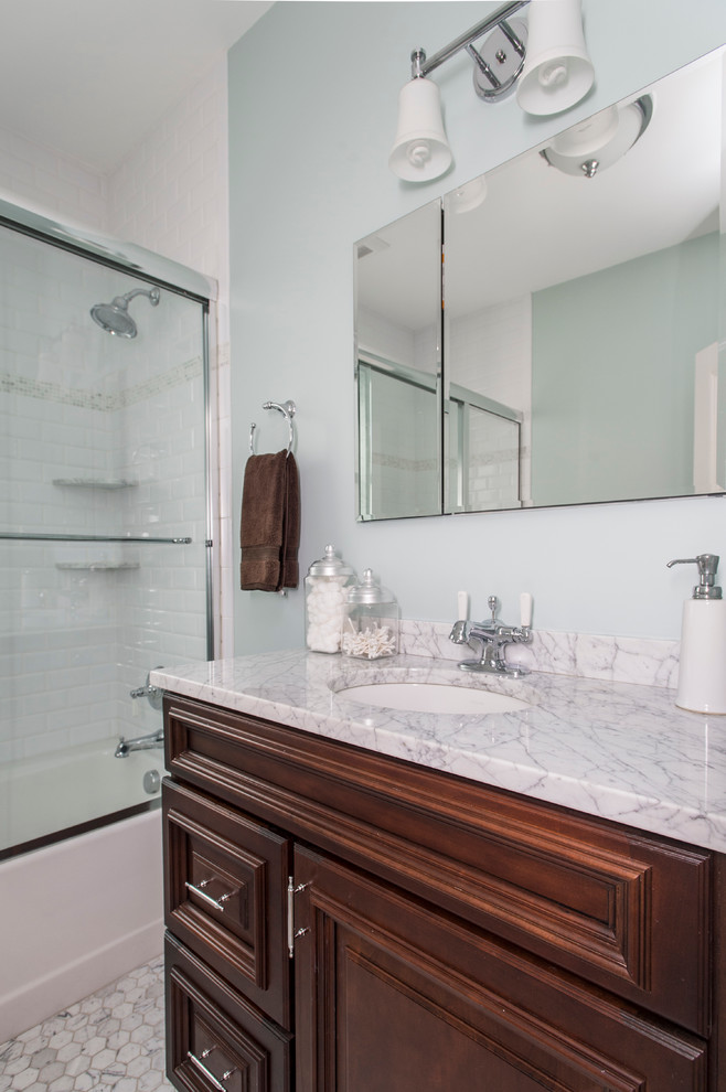 Small transitional white tile and ceramic tile marble floor alcove bathtub photo in Boston with recessed-panel cabinets, dark wood cabinets, a two-piece toilet, blue walls, an undermount sink and marble countertops