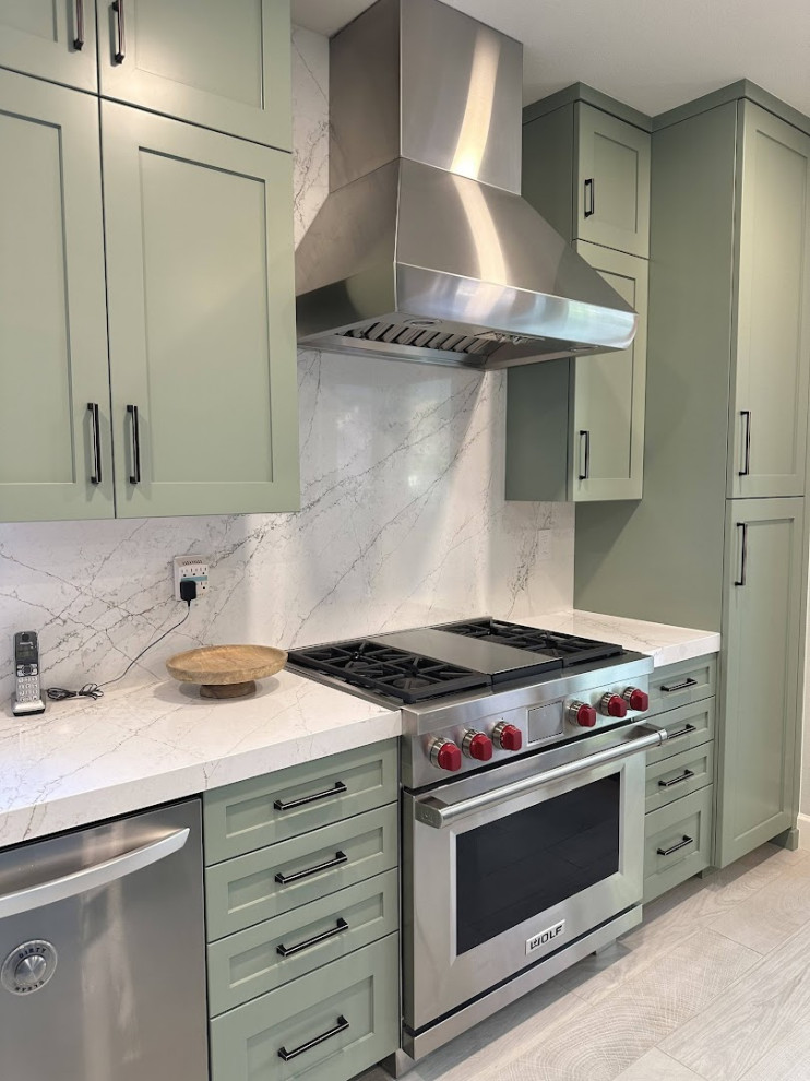 This is an example of a mid-sized transitional galley kitchen pantry in Orange County with an undermount sink, shaker cabinets, green cabinets, laminate benchtops, white splashback, stainless steel appliances, ceramic floors, with island, multi-coloured floor, white benchtop and vaulted.