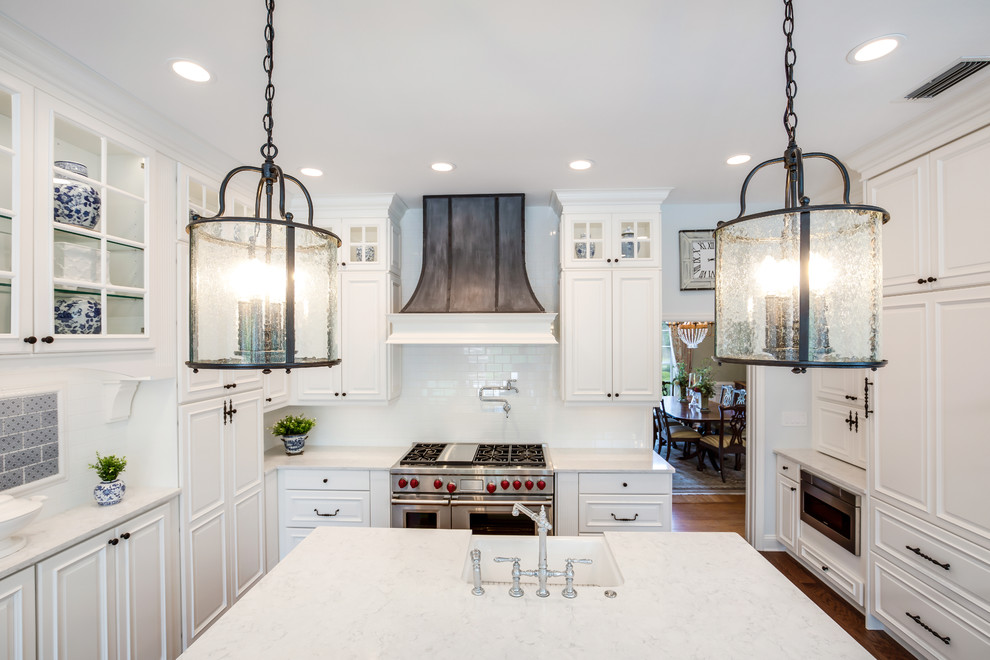 This is an example of a mid-sized u-shaped eat-in kitchen in Jacksonville with a farmhouse sink, raised-panel cabinets, white cabinets, quartz benchtops, white splashback, subway tile splashback, stainless steel appliances, vinyl floors, with island, brown floor and white benchtop.