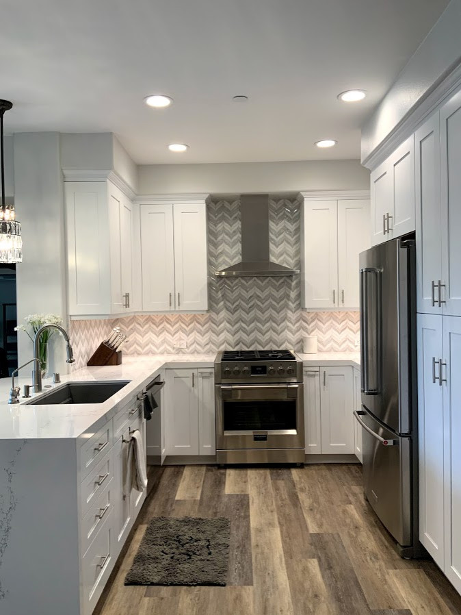 Small modern u-shaped eat-in kitchen in Los Angeles with a single-bowl sink, recessed-panel cabinets, white cabinets, quartz benchtops, mosaic tile splashback, stainless steel appliances, vinyl floors, a peninsula and white benchtop.