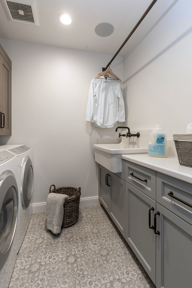 Mid-sized utility room in San Francisco with a drop-in sink, glass-front cabinets, medium wood cabinets, quartz benchtops, white walls, ceramic floors, a side-by-side washer and dryer, multi-coloured floor and white benchtop.