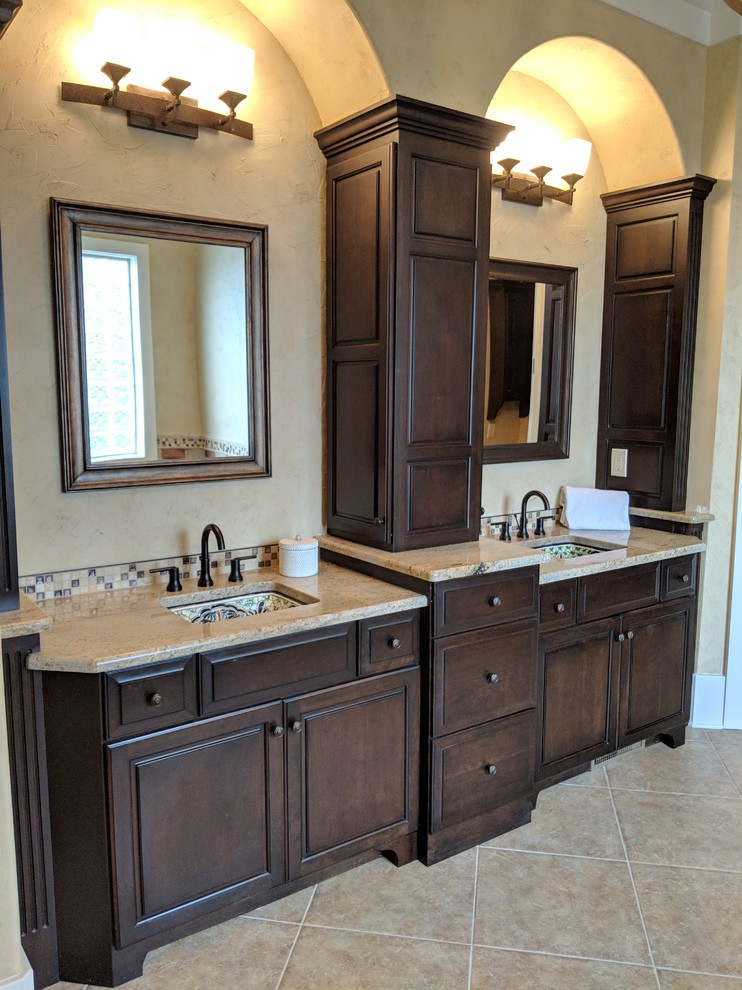 Mid-sized country bathroom in Other with raised-panel cabinets, dark wood cabinets, a freestanding tub, porcelain tile, ceramic floors, an undermount sink, granite benchtops and brown benchtops.