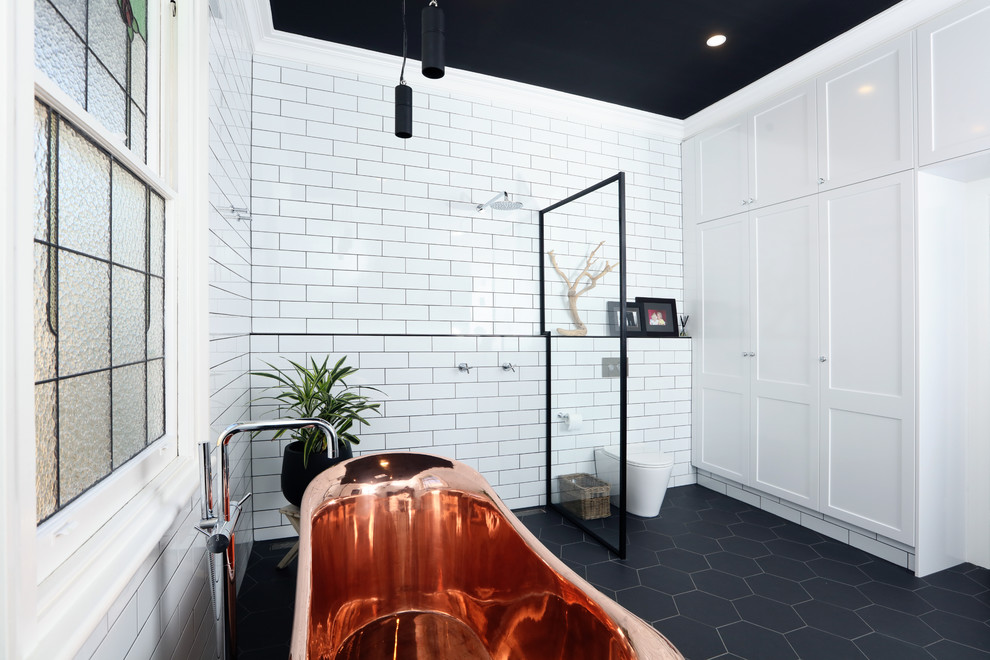 Contemporary bathroom in Melbourne with subway tile, porcelain floors, concrete benchtops, white tile, white walls, black floor, an open shower, a single vanity and brick walls.