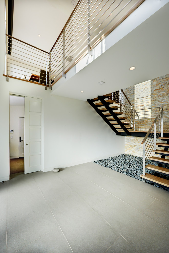 This is an example of a large contemporary wood u-shaped staircase in Orange County with open risers.