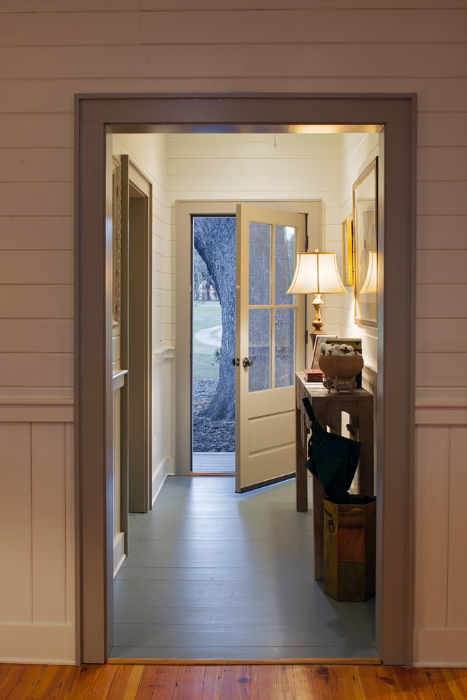 Large country entry hall in Charleston with white walls, light hardwood floors and a single front door.
