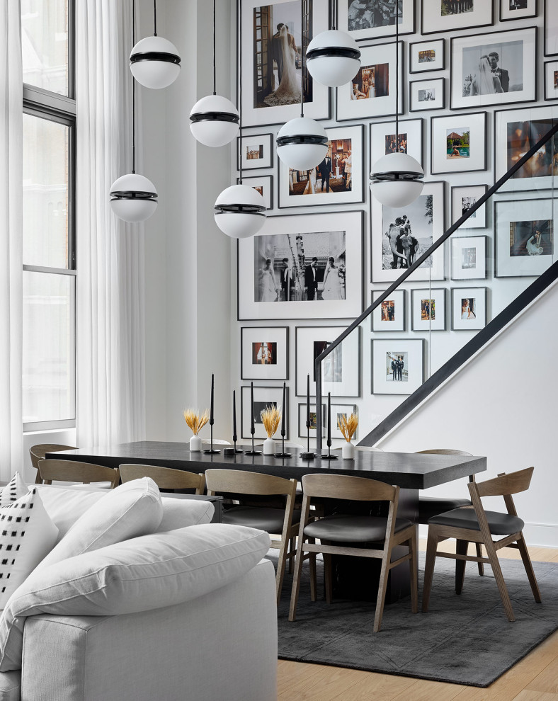 Immagine di una sala da pranzo aperta verso il soggiorno contemporanea con pareti bianche e parquet chiaro