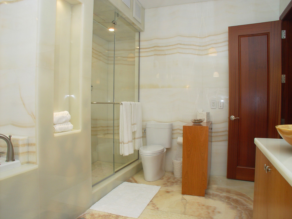 Inspiration for a large modern master bathroom in Miami with flat-panel cabinets, light wood cabinets, a corner tub, a corner shower, a two-piece toilet, multi-coloured tile, stone slab, multi-coloured walls, marble floors, a vessel sink, onyx benchtops, multi-coloured floor and a sliding shower screen.