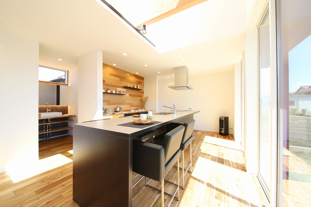 Modern single-wall open plan kitchen in Tokyo with an undermount sink, beaded inset cabinets, dark wood cabinets, stainless steel appliances, medium hardwood floors, with island, brown floor and beige benchtop.
