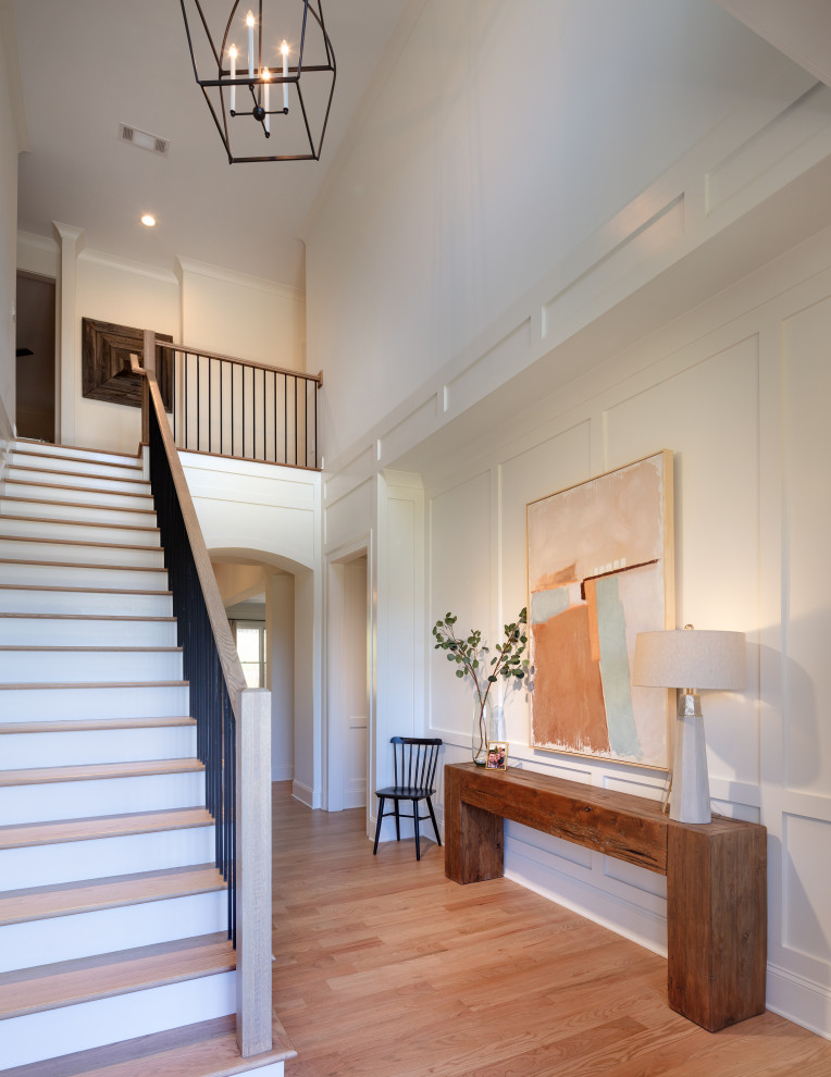 Large transitional foyer in Atlanta with white walls, light hardwood floors, a double front door, brown floor, vaulted and panelled walls.