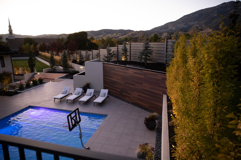 Design ideas for a modern backyard garden in Salt Lake City with a retaining wall, concrete pavers and a vinyl fence.