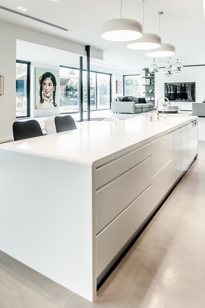 Photo of a large contemporary galley eat-in kitchen in Melbourne with a double-bowl sink, flat-panel cabinets, black cabinets, solid surface benchtops, metallic splashback, glass sheet splashback, stainless steel appliances, concrete floors and with island.