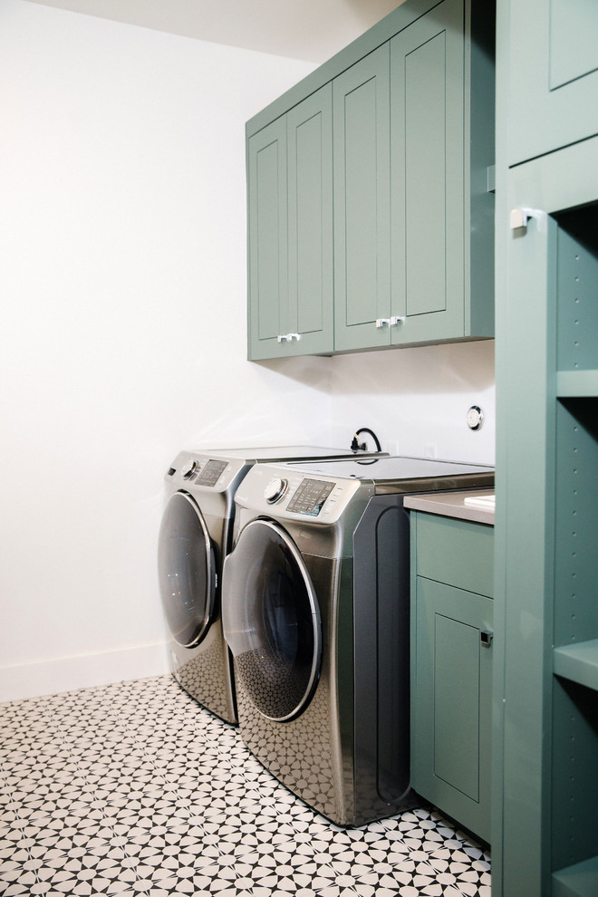 Mid-sized transitional single-wall dedicated laundry room in Austin with a drop-in sink, recessed-panel cabinets, blue cabinets, quartz benchtops, white walls, ceramic floors, a side-by-side washer and dryer, multi-coloured floor and grey benchtop.