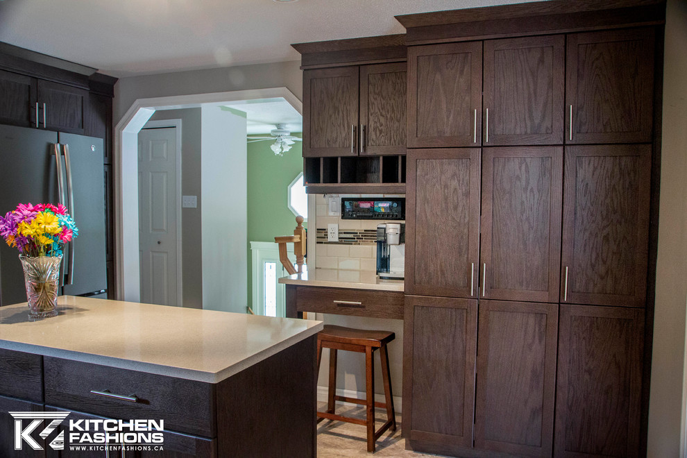 Example of a mid-sized transitional l-shaped enclosed kitchen design in Toronto with an undermount sink, shaker cabinets, dark wood cabinets, quartz countertops, multicolored backsplash, subway tile backsplash, stainless steel appliances and an island