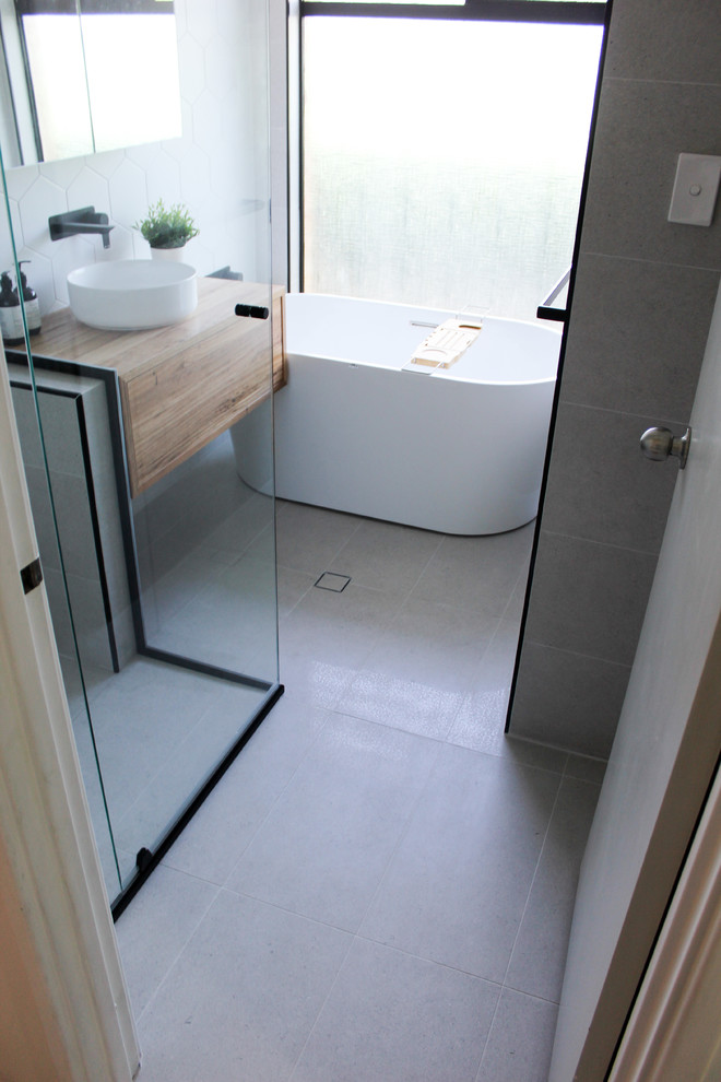 This is an example of a small modern kids bathroom in Perth with furniture-like cabinets, dark wood cabinets, a freestanding tub, a corner shower, white tile, mosaic tile, white walls, porcelain floors, a vessel sink, wood benchtops, grey floor, a hinged shower door and brown benchtops.