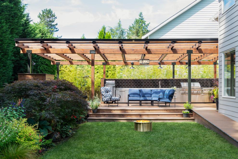 Example of a mid-sized trendy backyard ground level outdoor kitchen deck design in Seattle with a pergola