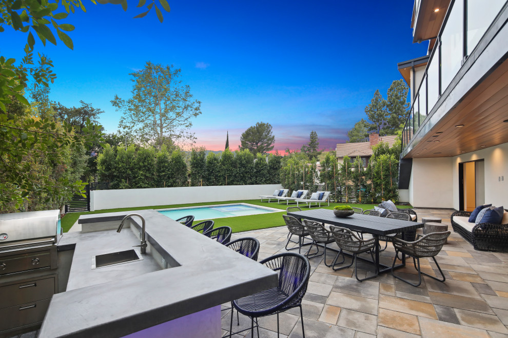 Design ideas for a large contemporary backyard patio in Los Angeles with natural stone pavers and no cover.