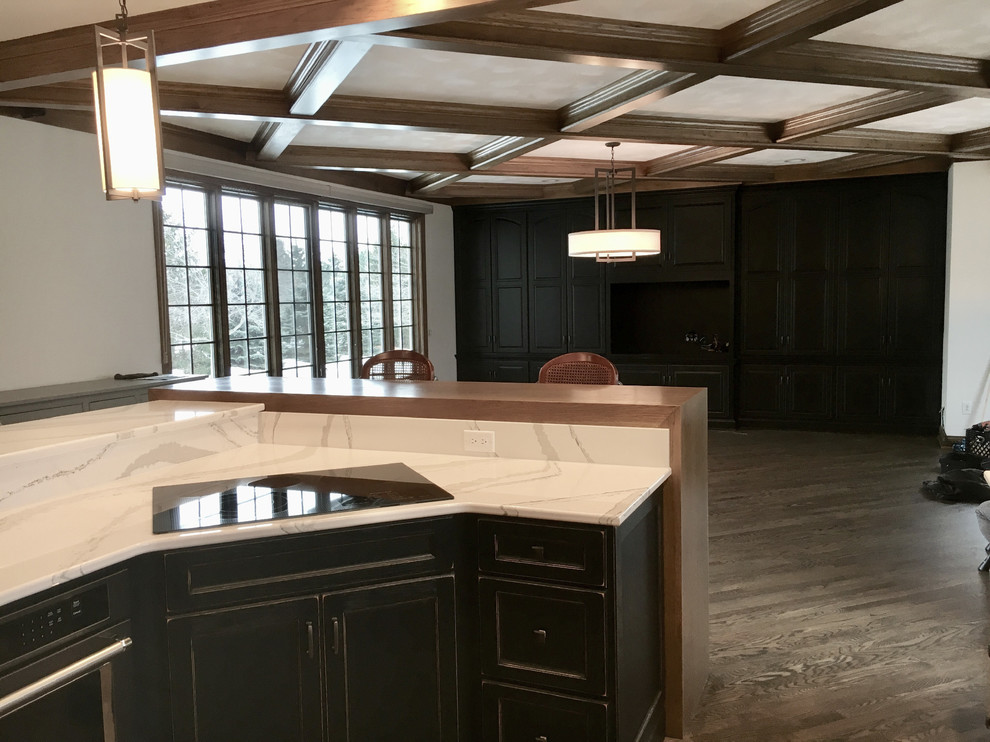 Large transitional u-shaped medium tone wood floor open concept kitchen photo with an undermount sink, recessed-panel cabinets, distressed cabinets, quartz countertops, multicolored backsplash, mosaic tile backsplash, stainless steel appliances and an island