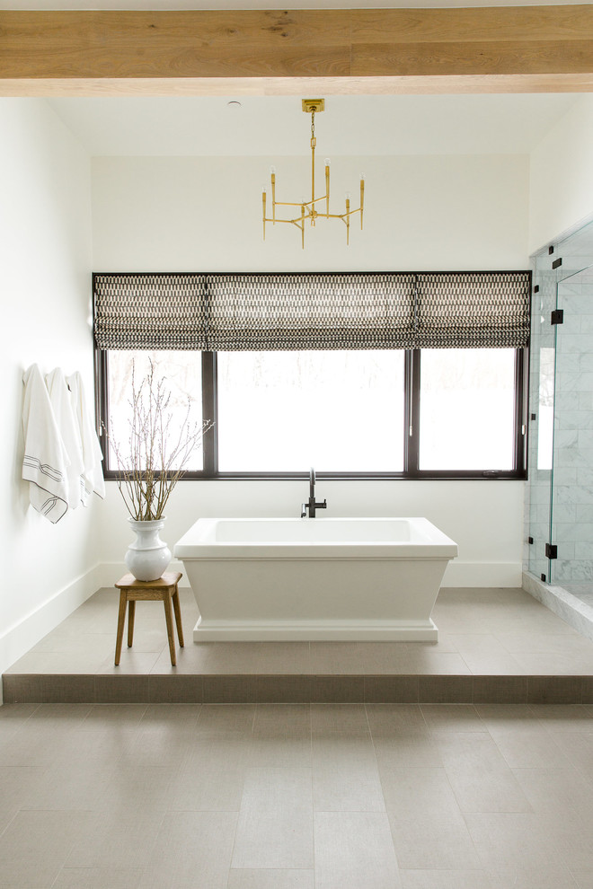 This is an example of a transitional master bathroom in Salt Lake City with white walls, a freestanding tub and a hinged shower door.
