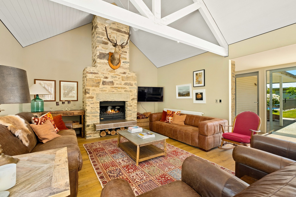 Photo of a Large country Open Concept living room With Beige Walls, Medium Hardwood Floors, a Wood Stove, a Wall-mounted TV, Brown Floor and Exposed Beam.