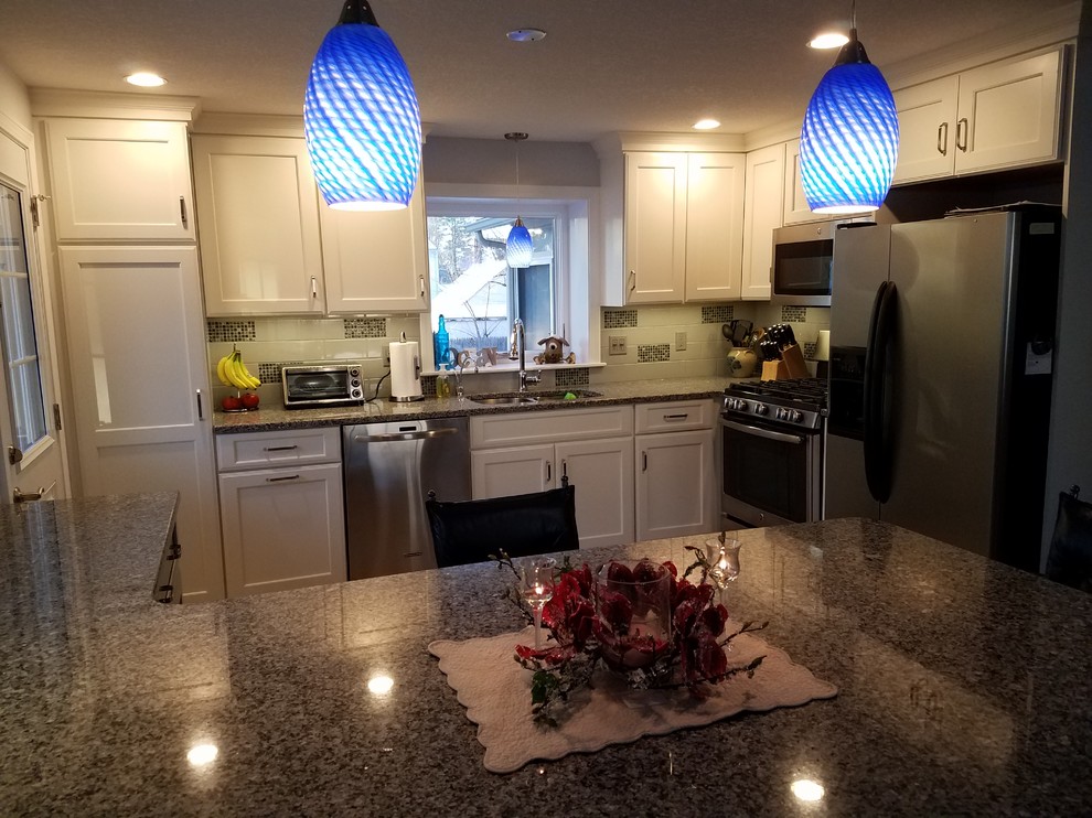 Example of a mid-sized transitional eat-in kitchen design in Boston with a double-bowl sink, shaker cabinets, white cabinets, granite countertops, white backsplash, ceramic backsplash, stainless steel appliances and a peninsula