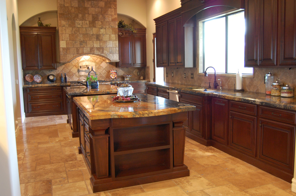 Expansive traditional galley eat-in kitchen in Phoenix with multiple islands, an undermount sink, raised-panel cabinets, dark wood cabinets, granite benchtops, beige splashback, stone tile splashback, stainless steel appliances and travertine floors.