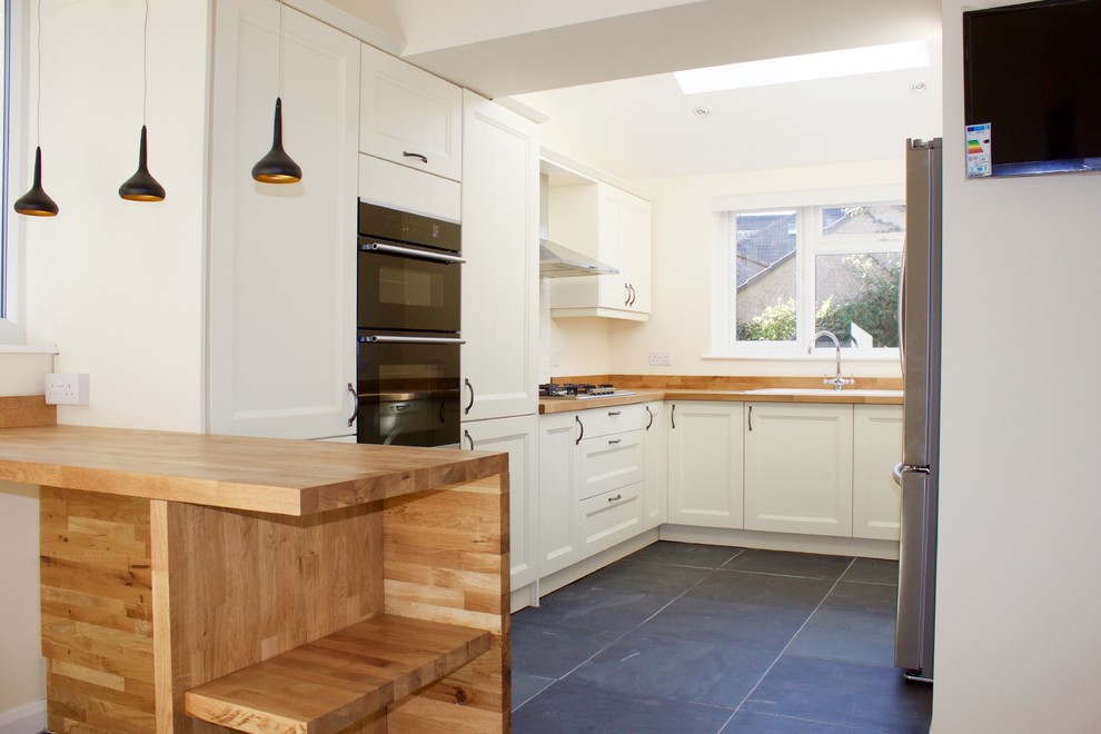 Inspiration for a mid-sized u-shaped eat-in kitchen in Other with wood benchtops, ceramic splashback, stainless steel appliances, slate floors and no island.