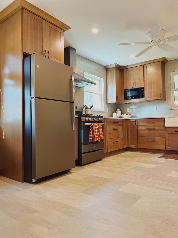 Eat-in kitchen - mid-sized transitional l-shaped vinyl floor and beige floor eat-in kitchen idea with a farmhouse sink, shaker cabinets, medium tone wood cabinets, quartzite countertops, green backsplash, ceramic backsplash, stainless steel appliances, no island and beige countertops