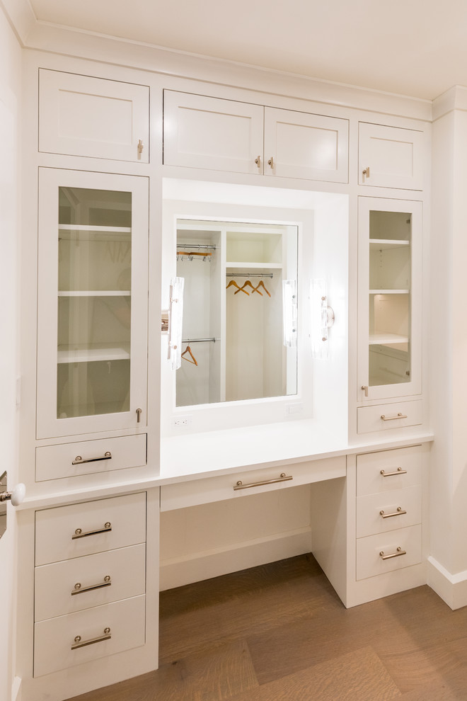 Design ideas for a small beach style gender-neutral walk-in wardrobe in New York with recessed-panel cabinets, white cabinets, light hardwood floors and beige floor.