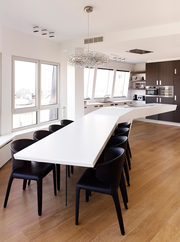 Design ideas for a contemporary galley eat-in kitchen in Melbourne with solid surface benchtops, dark wood cabinets, white splashback, stainless steel appliances, light hardwood floors and with island.