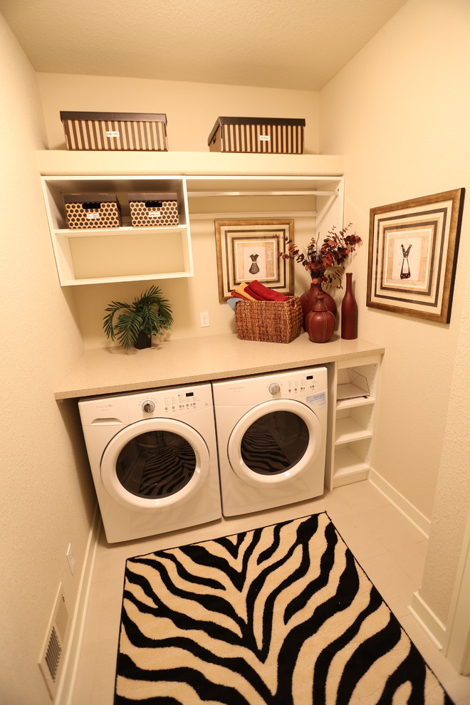 Modelo de cuarto de lavado lineal clásico renovado pequeño con armarios abiertos, puertas de armario blancas, encimera de acrílico, paredes beige, suelo de baldosas de cerámica y lavadora y secadora juntas