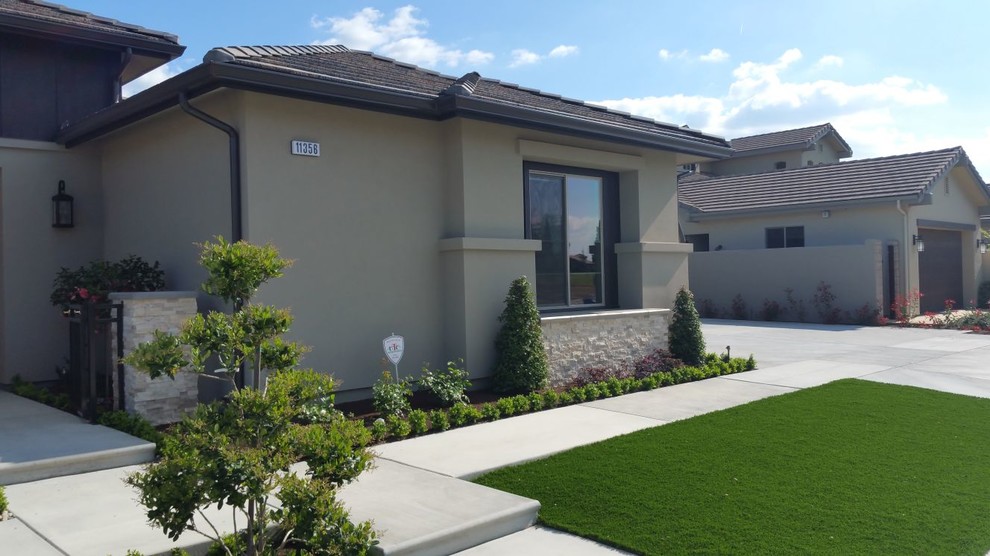 Large transitional beige one-story stucco gable roof photo with a tile roof