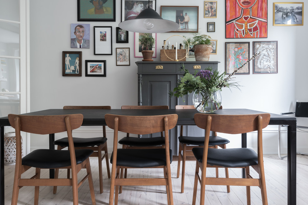 This is an example of a scandinavian dining room in Stockholm with white walls, light hardwood floors and white floor.