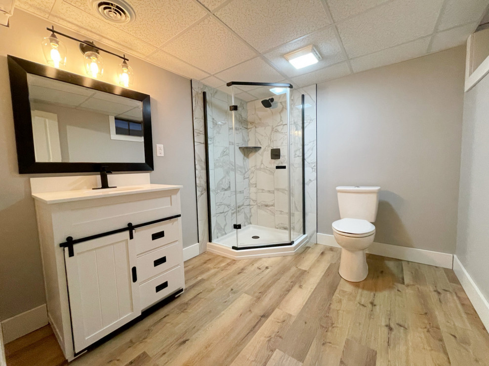 Inspiration for a mid-sized modern bathroom in Detroit with shaker cabinets, white cabinets, a corner shower, a one-piece toilet, multi-coloured tile, marble, grey walls, vinyl floors, a drop-in sink, engineered quartz benchtops, brown floor, a hinged shower door, white benchtops, a single vanity, a floating vanity and recessed.