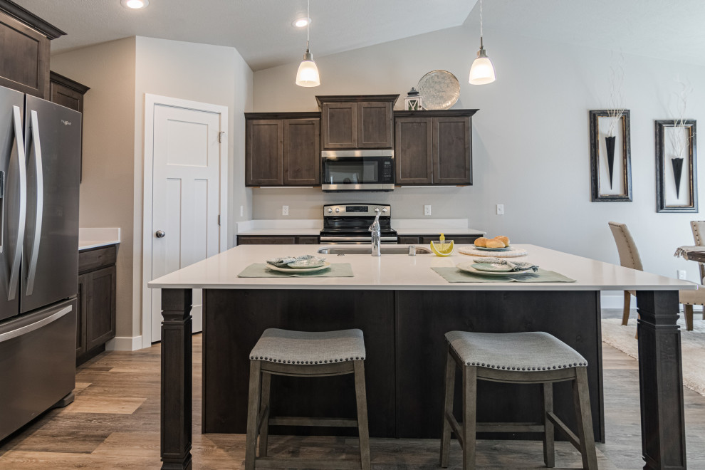 Example of a mid-sized transitional l-shaped vinyl floor and gray floor eat-in kitchen design with an undermount sink, shaker cabinets, dark wood cabinets, quartz countertops, quartz backsplash, stainless steel appliances, an island and white countertops