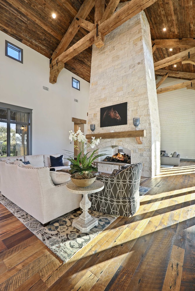 Country open concept living room in Austin with beige walls, medium hardwood floors, a two-sided fireplace, a stone fireplace surround and brown floor.