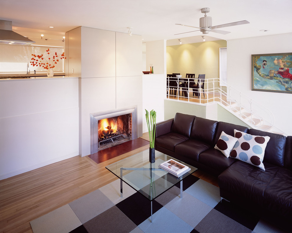 This is an example of a mid-sized contemporary open concept living room in San Francisco with white walls, a standard fireplace, light hardwood floors, a metal fireplace surround and no tv.