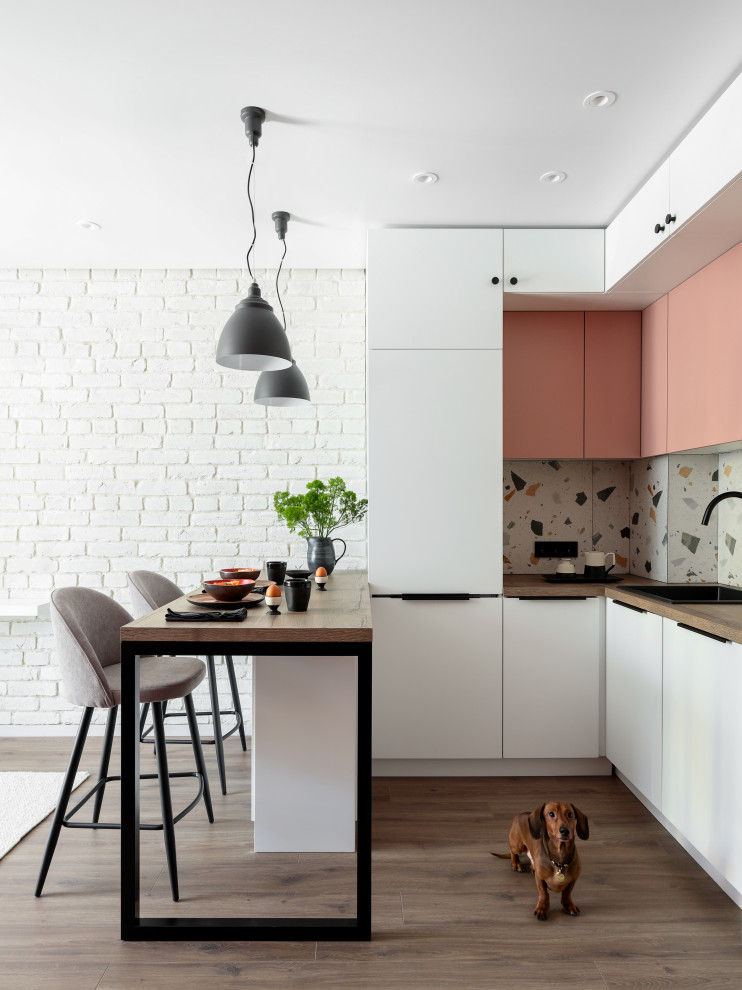 Пример оригинального дизайна: маленькая угловая кухня в скандинавском стиле с обеденным столом, одинарной мойкой, плоскими фасадами, розовыми фасадами, деревянной столешницей, разноцветным фартуком, фартуком из керамогранитной плитки, техникой из нержавеющей стали, паркетным полом среднего тона, коричневым полом, коричневой столешницей и двухцветным гарнитуром для на участке и в саду